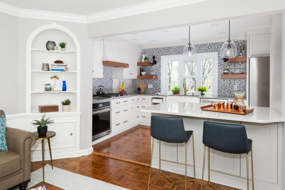 Ejemplo de cocinas en L clásica renovada, pequeña, abierta, con fregadero sobremueble, armarios con rebordes decorativos, puertas de armario blancas, encimera de cuarzo compacto, salpicadero azul, salpicadero de azulejos de terracota, electrodomésticos de acero inoxidable, suelo de madera en tonos medios, península, suelo marrón y encimeras grises