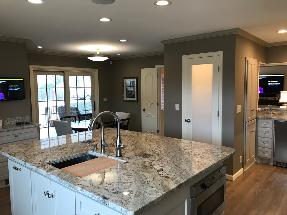 Inspiration for a large transitional l-shaped light wood floor and gray floor eat-in kitchen remodel in Other with an undermount sink, shaker cabinets, gray cabinets, granite countertops, gray backsplash, glass tile backsplash, stainless steel appliances and an island