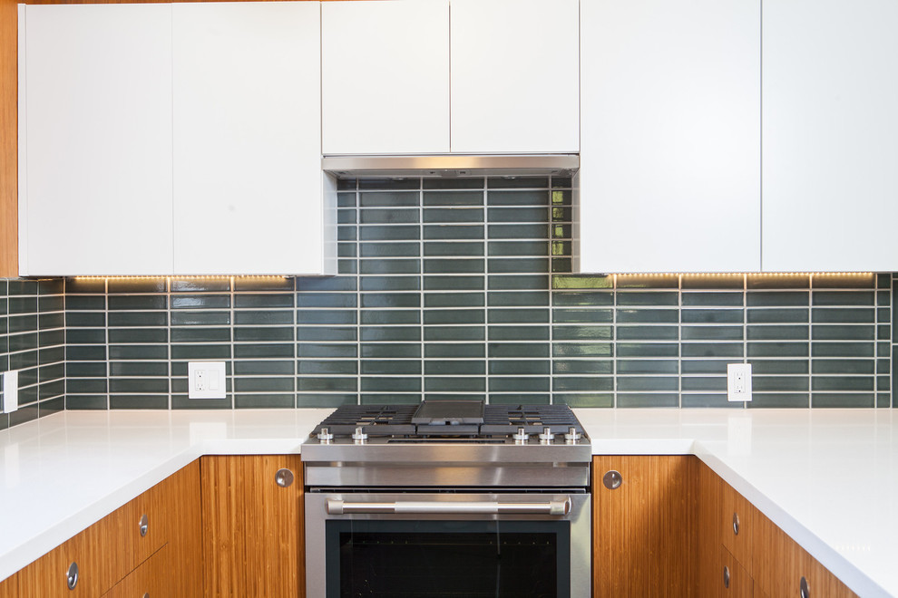 Example of a 1960s u-shaped vinyl floor kitchen design in San Francisco with an undermount sink, flat-panel cabinets, medium tone wood cabinets, quartz countertops, green backsplash, ceramic backsplash, stainless steel appliances and a peninsula