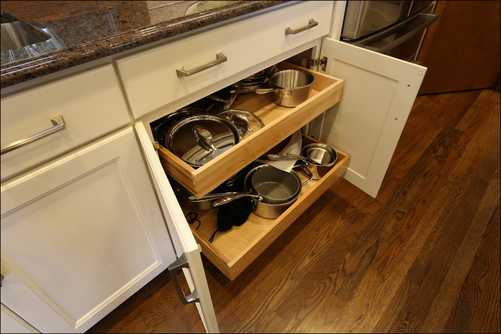 Inredning av ett klassiskt mellanstort brun brunt kök och matrum, med en undermonterad diskho, luckor med infälld panel, vita skåp, granitbänkskiva, brunt stänkskydd, stänkskydd i glaskakel, rostfria vitvaror, mellanmörkt trägolv, en köksö och brunt golv