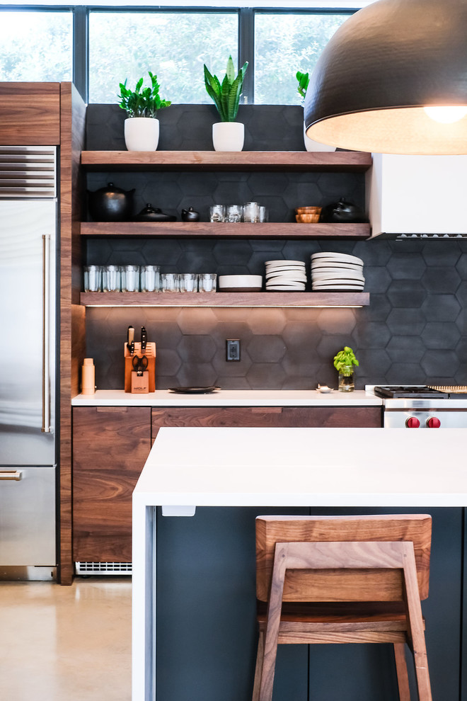 Inspiration for a large contemporary l-shaped open plan kitchen in Other with a submerged sink, flat-panel cabinets, medium wood cabinets, engineered stone countertops, black splashback, cement tile splashback, stainless steel appliances, concrete flooring, an island and grey floors.