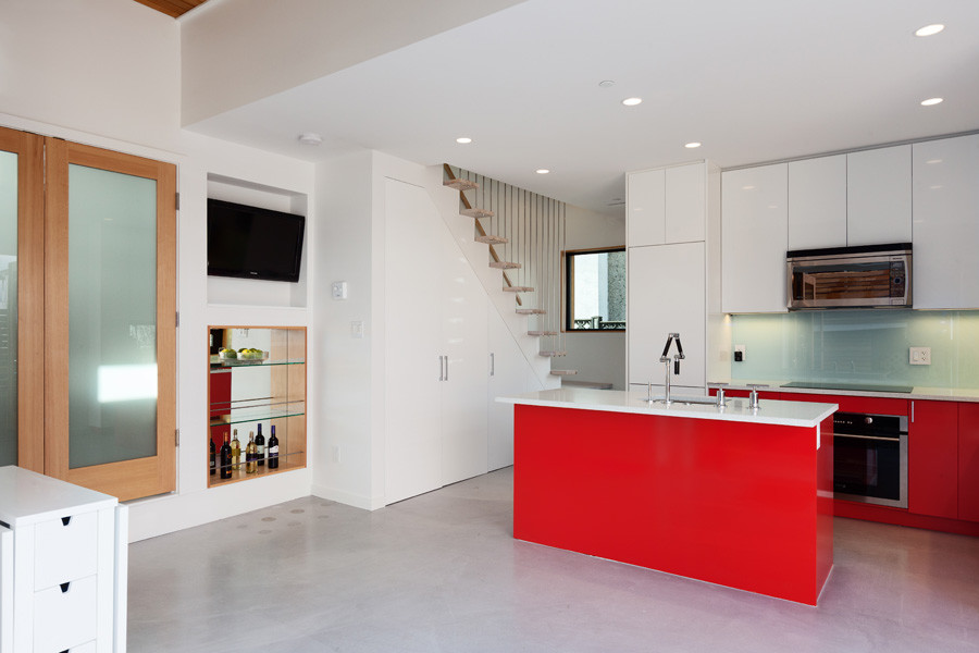Minimalist l-shaped concrete floor open concept kitchen photo in Vancouver with an undermount sink, flat-panel cabinets, red cabinets, quartz countertops, blue backsplash, glass sheet backsplash, stainless steel appliances and an island