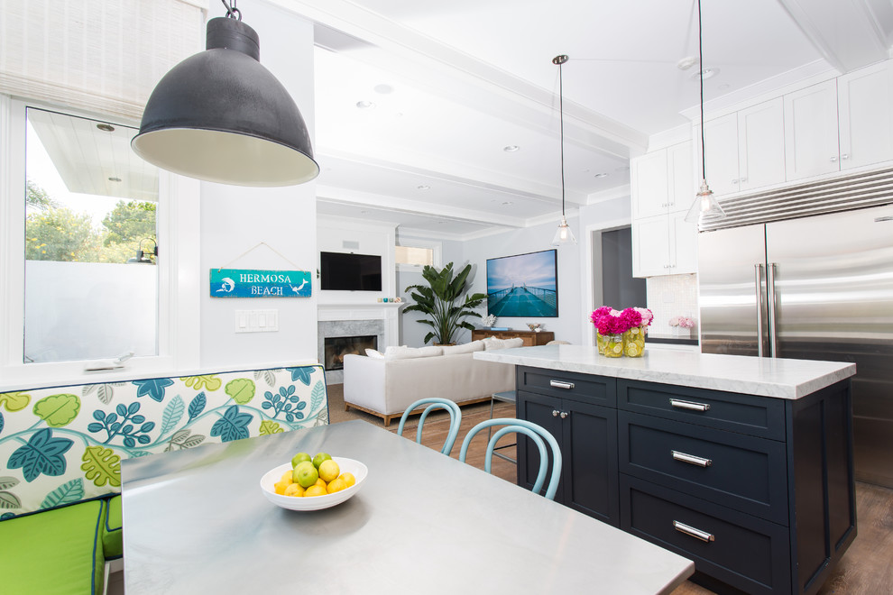 Beach style u-shaped dark wood floor open concept kitchen photo in Los Angeles with a farmhouse sink, shaker cabinets, white cabinets, marble countertops, white backsplash, an island and stainless steel appliances