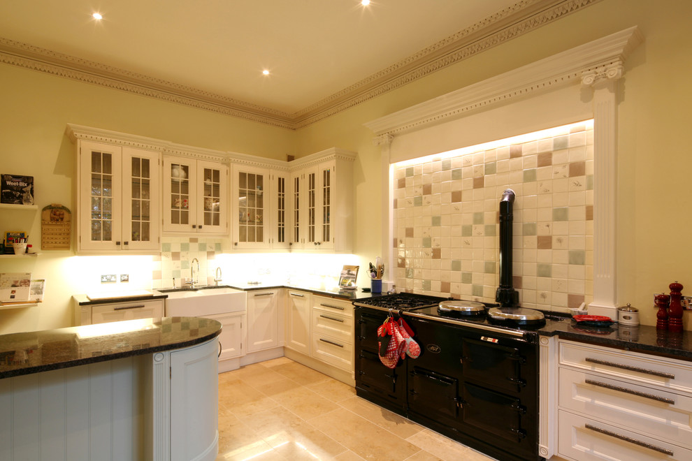 Example of a mid-sized country l-shaped travertine floor eat-in kitchen design in Edinburgh with a farmhouse sink, shaker cabinets, blue cabinets, granite countertops, paneled appliances and an island