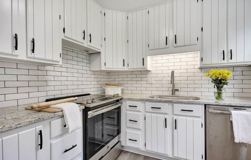 Example of a small trendy u-shaped vinyl floor and gray floor enclosed kitchen design in Other with a single-bowl sink, beaded inset cabinets, white cabinets, granite countertops, ceramic backsplash, stainless steel appliances and multicolored countertops