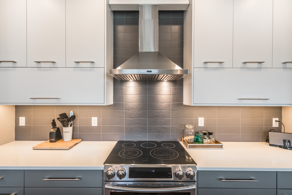 Immagine di una cucina moderna di medie dimensioni con lavello a doppia vasca, ante in stile shaker, ante grigie, paraspruzzi grigio, elettrodomestici in acciaio inossidabile, pavimento in legno massello medio, pavimento marrone e top bianco