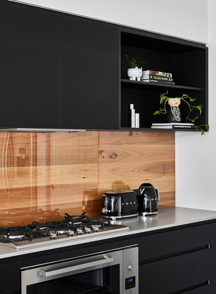 Design ideas for a beach style kitchen in Sunshine Coast with flat-panel cabinets, black cabinets, window splashback, stainless steel appliances and grey worktops.