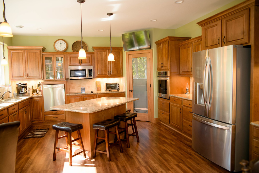 Example of a mid-sized classic u-shaped dark wood floor and brown floor enclosed kitchen design in Other with an undermount sink, raised-panel cabinets, medium tone wood cabinets, glass countertops, beige backsplash, ceramic backsplash, stainless steel appliances and an island