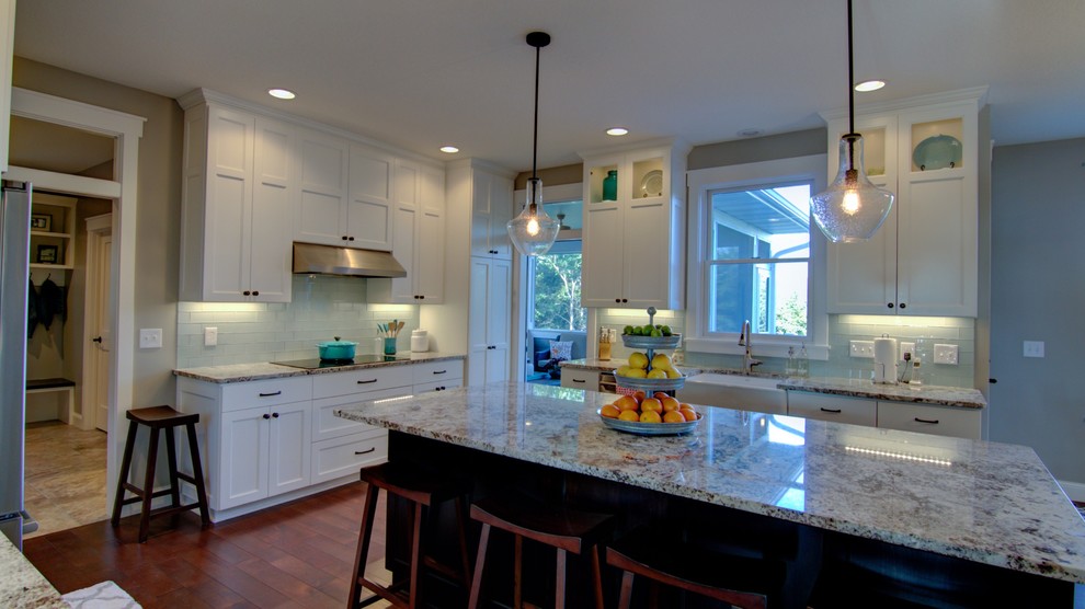 Inspiration for a mid-sized transitional u-shaped dark wood floor eat-in kitchen remodel in Orange County with a farmhouse sink, raised-panel cabinets, white cabinets, granite countertops, white backsplash, subway tile backsplash, stainless steel appliances and an island