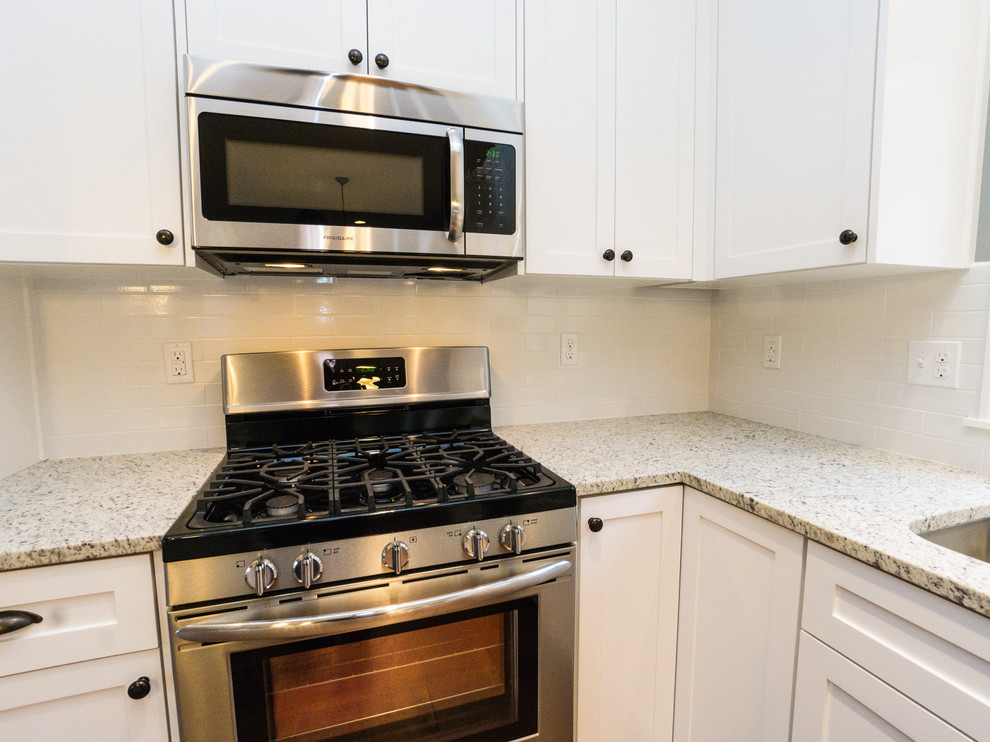 Mid-sized elegant l-shaped medium tone wood floor eat-in kitchen photo in Portland with an undermount sink, recessed-panel cabinets, white cabinets, granite countertops, white backsplash, subway tile backsplash, stainless steel appliances and an island