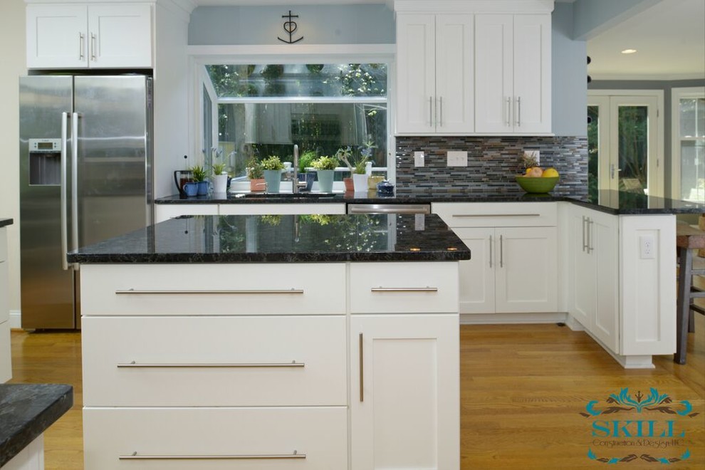 Modern inredning av ett stort kök, med en undermonterad diskho, luckor med infälld panel, vita skåp, granitbänkskiva, flerfärgad stänkskydd, stänkskydd i glaskakel, rostfria vitvaror, ljust trägolv och en köksö