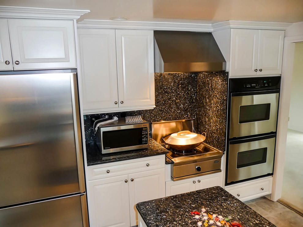 This is an example of a medium sized traditional u-shaped kitchen/diner in San Diego with a submerged sink, raised-panel cabinets, white cabinets, granite worktops, stone slab splashback, stainless steel appliances, vinyl flooring and an island.