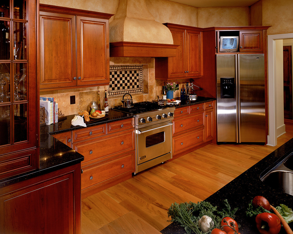 На фото: кухня в классическом стиле с фасадами с выступающей филенкой, техникой из нержавеющей стали, врезной мойкой, темными деревянными фасадами, разноцветным фартуком и телевизором с