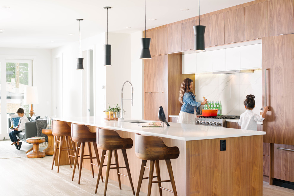 Zweizeilige Moderne Küche mit Unterbauwaschbecken, flächenbündigen Schrankfronten, hellbraunen Holzschränken, Küchenrückwand in Weiß, Elektrogeräten mit Frontblende, hellem Holzboden und Kücheninsel in Calgary