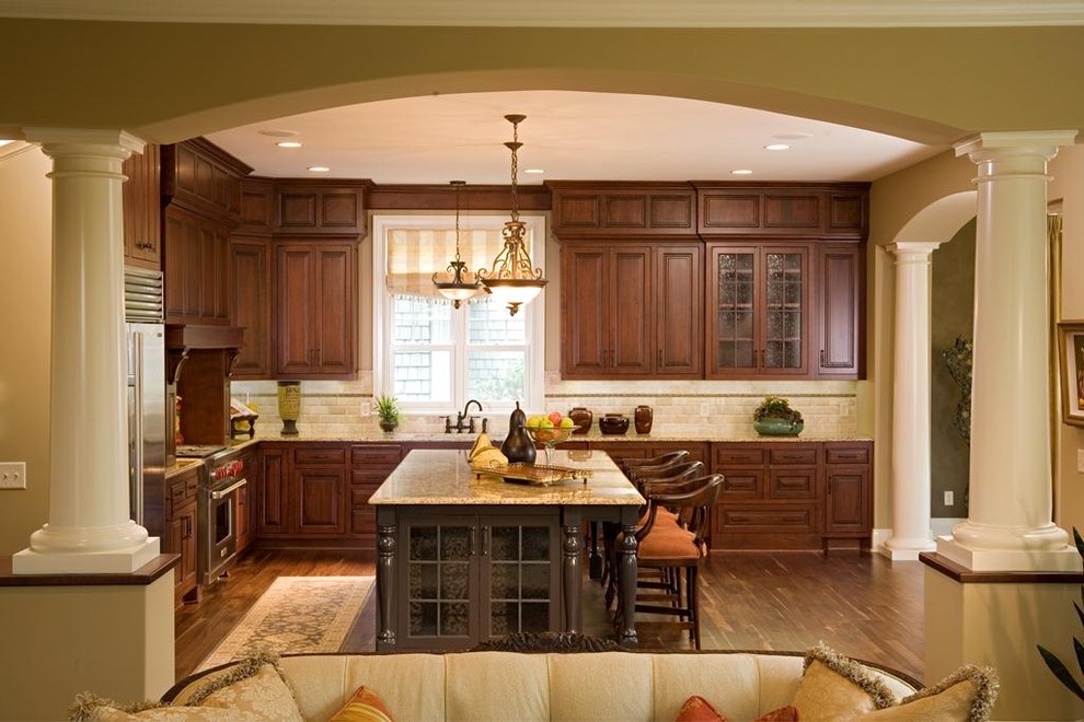 На фото: кухня-гостиная в классическом стиле с фасадами с выступающей филенкой, темными деревянными фасадами, бежевым фартуком и фартуком из плитки кабанчик