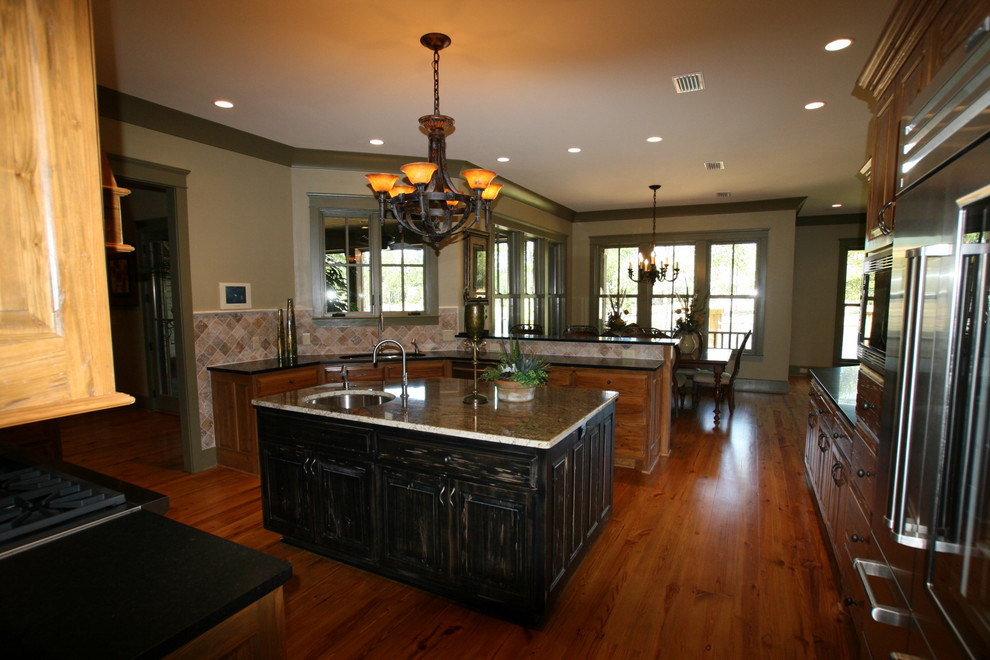 Пример оригинального дизайна: кухня в стиле кантри с обеденным столом, врезной мойкой, фасадами с выступающей филенкой, темными деревянными фасадами, разноцветным фартуком и техникой из нержавеющей стали
