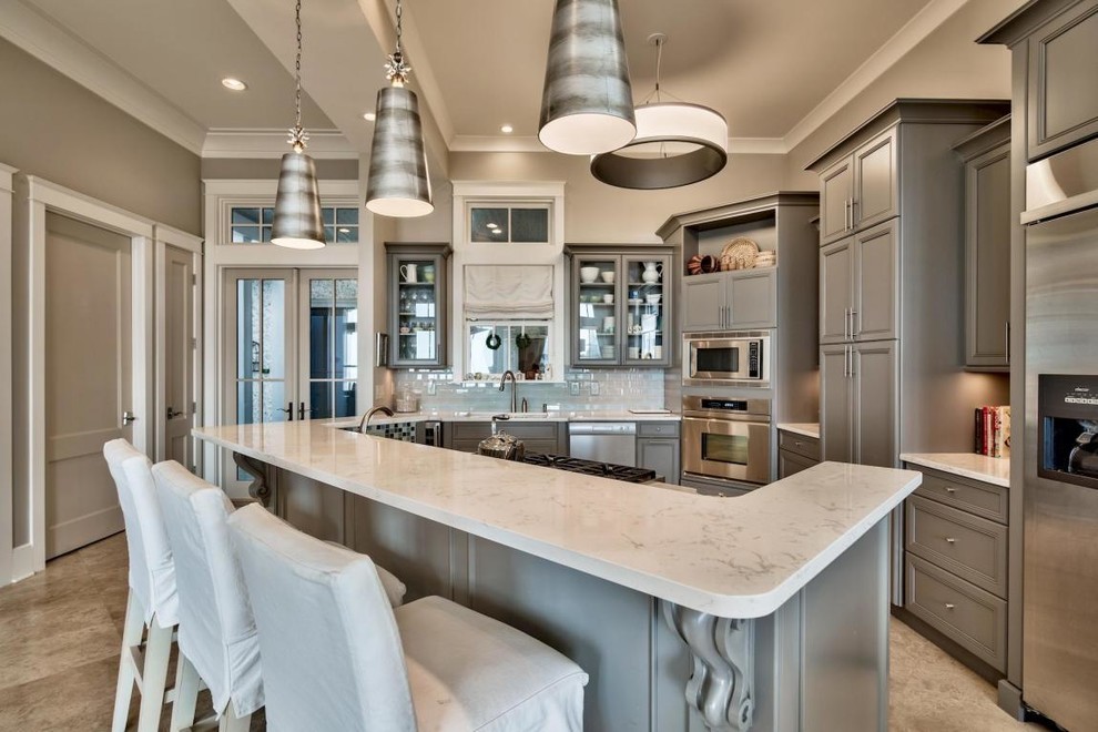 Example of a classic kitchen design with recessed-panel cabinets, gray cabinets, white backsplash, stainless steel appliances, an island and white countertops