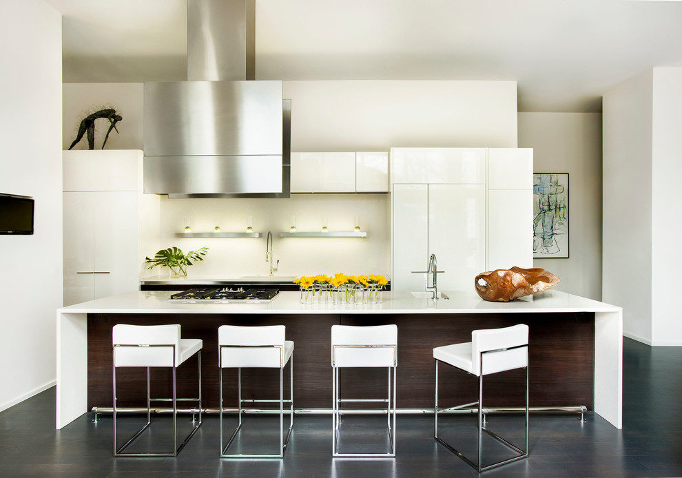 Example of a trendy galley open concept kitchen design in Atlanta with an integrated sink, flat-panel cabinets, white cabinets, solid surface countertops, white backsplash and paneled appliances