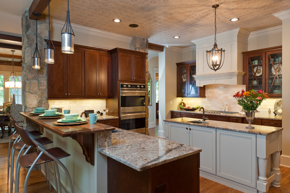 Immagine di una cucina classica con ante di vetro, elettrodomestici in acciaio inossidabile, ante in legno bruno e paraspruzzi beige