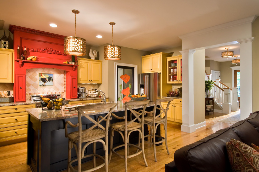 This is an example of a country l-shaped open plan kitchen in New York with raised-panel cabinets, yellow cabinets, multi-coloured splashback, stainless steel appliances, medium hardwood flooring and an island.