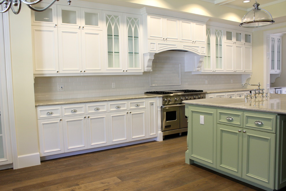 Example of a large classic l-shaped medium tone wood floor eat-in kitchen design in Los Angeles with a farmhouse sink, recessed-panel cabinets, white cabinets, granite countertops, white backsplash, subway tile backsplash, stainless steel appliances and an island