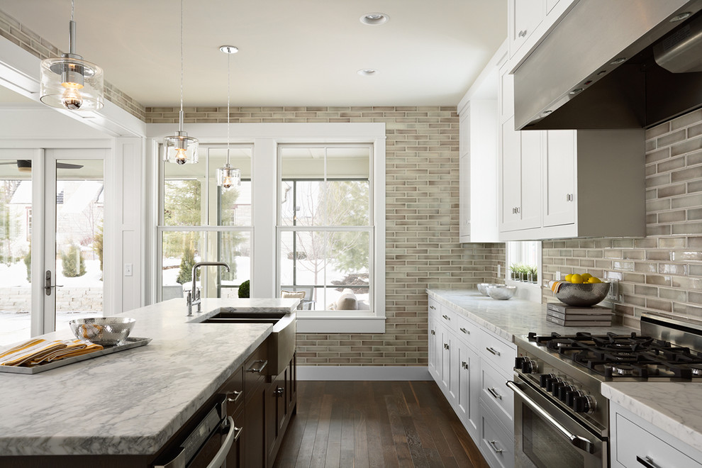 Example of a trendy galley kitchen design in Minneapolis with subway tile backsplash, a farmhouse sink, marble countertops, shaker cabinets, white cabinets, gray backsplash and stainless steel appliances