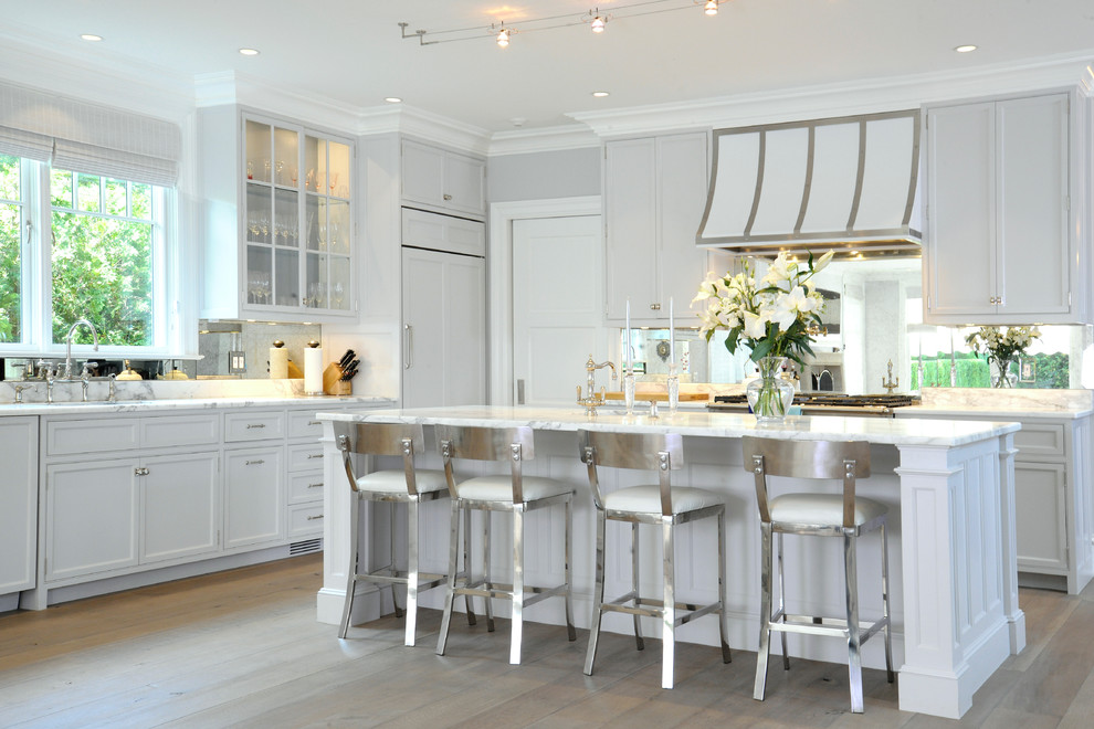 На фото: угловая кухня в классическом стиле с фасадами в стиле шейкер, серыми фасадами, фартуком цвета металлик, зеркальным фартуком и техникой под мебельный фасад с