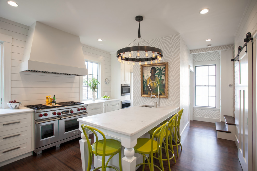 Foto de cocina clásica renovada con armarios estilo shaker, puertas de armario blancas, electrodomésticos de acero inoxidable, suelo de madera oscura y península