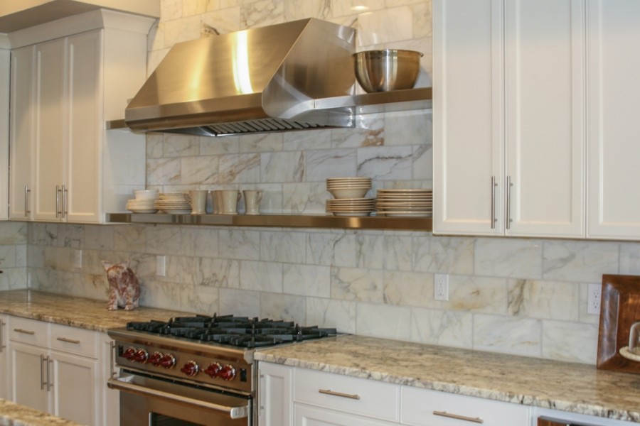 Cette image montre une cuisine design de taille moyenne avec un placard à porte shaker, un plan de travail en granite, une crédence beige, un électroménager en acier inoxydable et îlot.