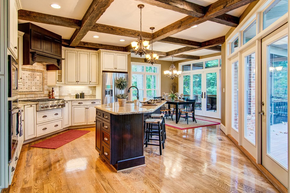 Example of a mid-sized classic u-shaped medium tone wood floor eat-in kitchen design in Other with a drop-in sink, beige cabinets, granite countertops, beige backsplash, stainless steel appliances and an island