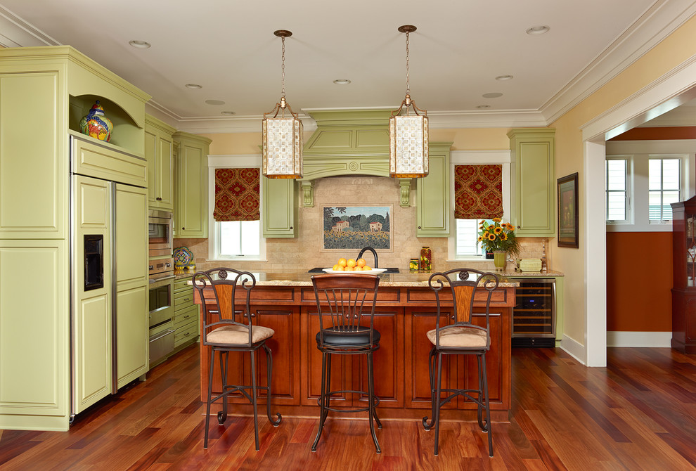 Klassisk inredning av ett kök, med granitbänkskiva, gröna skåp, luckor med upphöjd panel, integrerade vitvaror, en köksö och beige stänkskydd