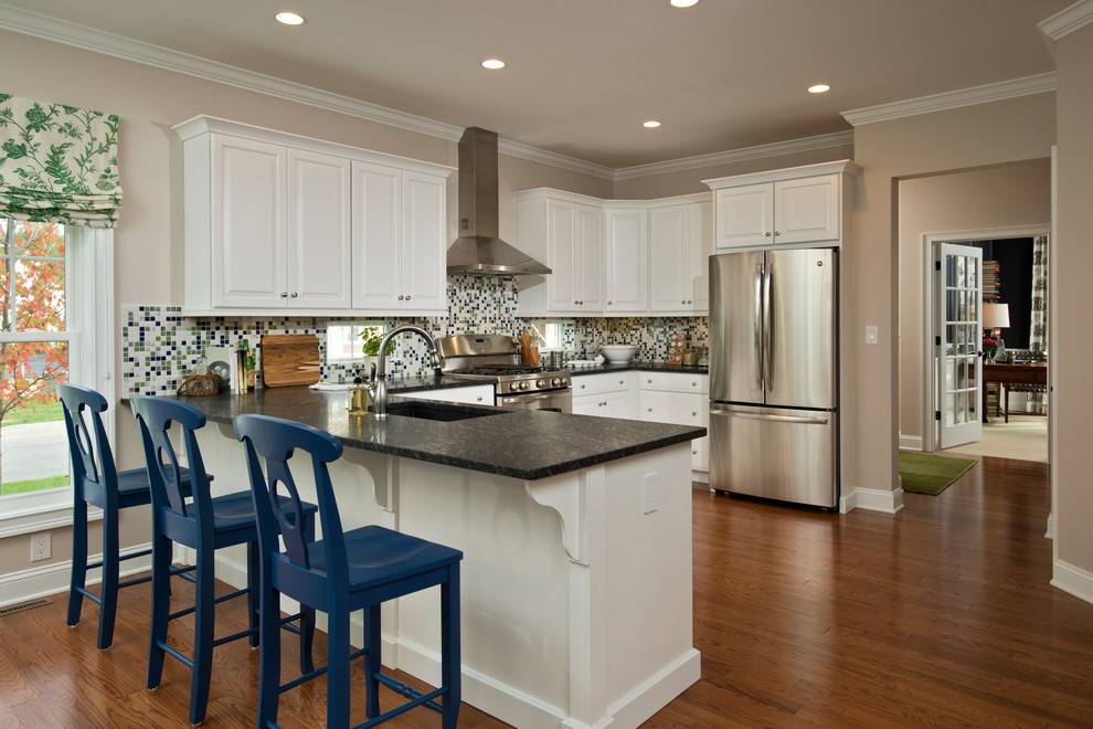 Eat-in kitchen - traditional medium tone wood floor eat-in kitchen idea in Boston with an undermount sink, raised-panel cabinets, white cabinets, granite countertops, multicolored backsplash, glass sheet backsplash, stainless steel appliances and a peninsula