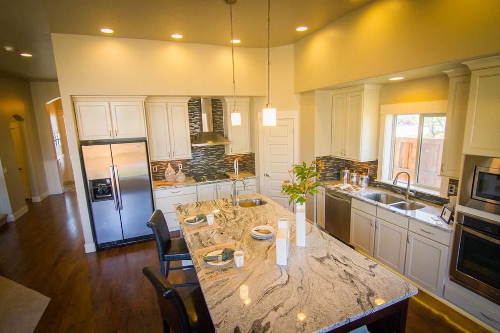 Example of a large trendy l-shaped medium tone wood floor eat-in kitchen design in Boise with an undermount sink, mosaic tile backsplash, stainless steel appliances, flat-panel cabinets, white cabinets, granite countertops, gray backsplash and an island