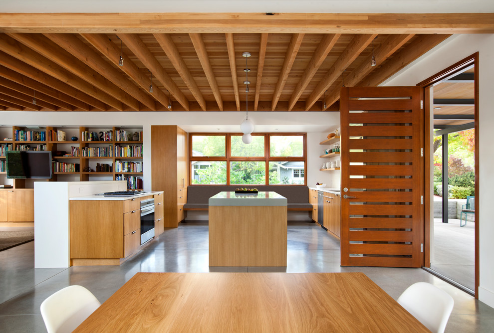 Exempel på ett modernt kök, med en undermonterad diskho, släta luckor, skåp i mellenmörkt trä, rostfria vitvaror, betonggolv och en köksö