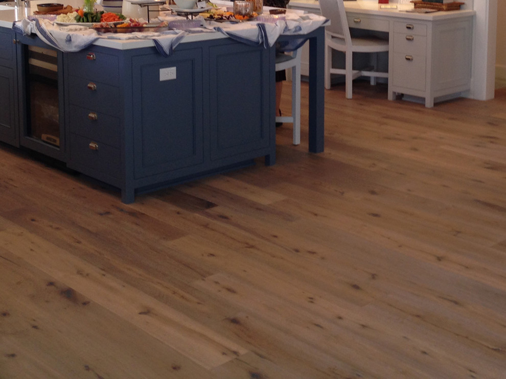 Cette image montre une cuisine marine avec des portes de placard bleues, un sol en bois brun et îlot.