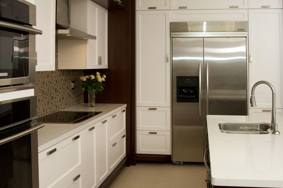 Photo of a large contemporary galley kitchen/diner in Toronto with a submerged sink, beaded cabinets, white cabinets, quartz worktops, beige splashback, metro tiled splashback, integrated appliances, travertine flooring and an island.