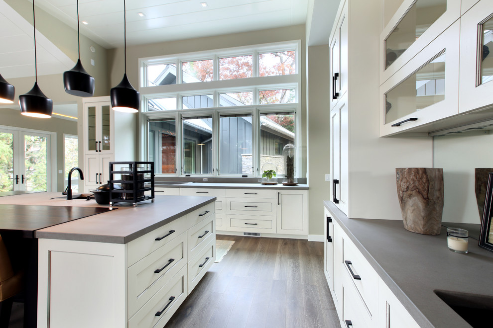 Exempel på ett stort klassiskt kök, med en undermonterad diskho, luckor med profilerade fronter, vita skåp, bänkskiva i betong, integrerade vitvaror, mellanmörkt trägolv och en köksö