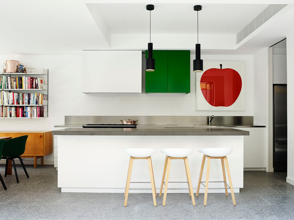 На фото: параллельная кухня среднего размера в современном стиле с обеденным столом, плоскими фасадами, белыми фасадами, островом и столешницей из нержавеющей стали с