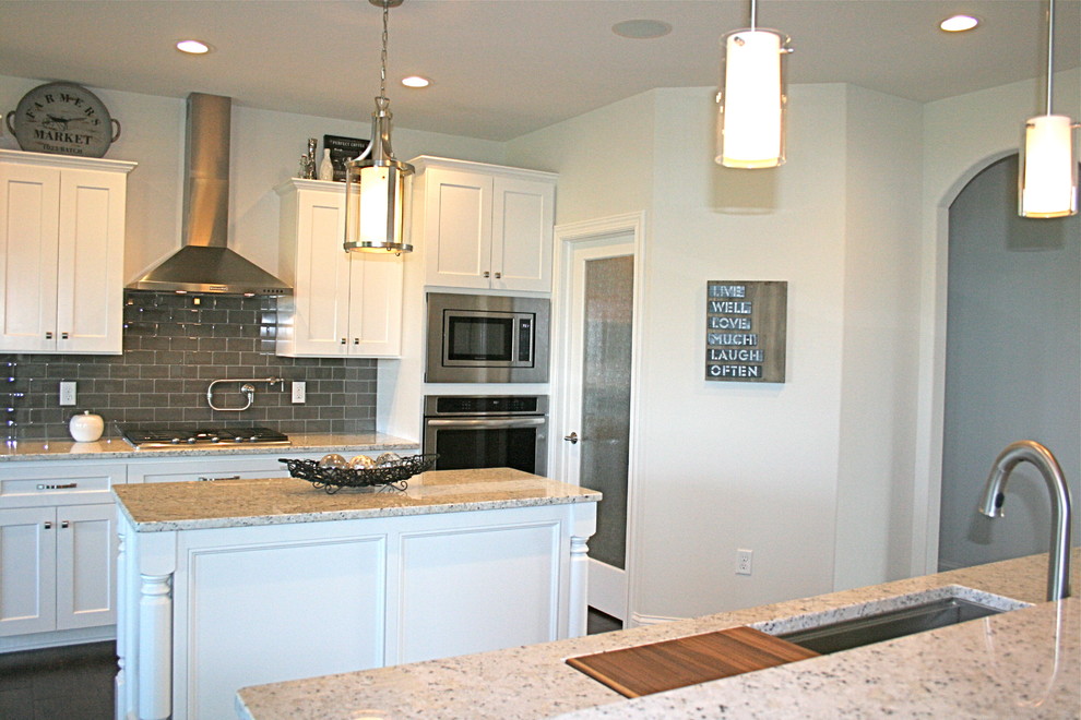 Exempel på ett stort klassiskt kök och matrum, med flera köksöar, släta luckor, vita skåp, granitbänkskiva, grått stänkskydd, stänkskydd i tunnelbanekakel, rostfria vitvaror, en undermonterad diskho och mörkt trägolv