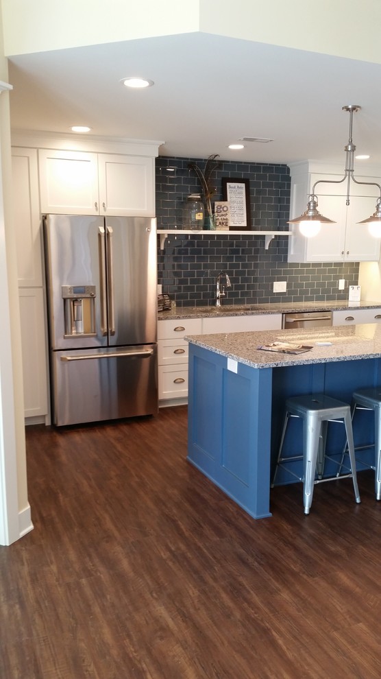 Kitchen - large contemporary l-shaped vinyl floor kitchen idea in Grand Rapids with an undermount sink, raised-panel cabinets, white cabinets, granite countertops, black backsplash, subway tile backsplash, stainless steel appliances and an island