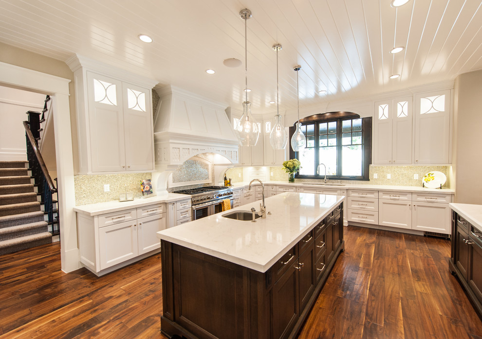Inspiration for a large transitional u-shaped medium tone wood floor and brown floor eat-in kitchen remodel in Salt Lake City with an undermount sink, shaker cabinets, white cabinets, quartz countertops, beige backsplash, mosaic tile backsplash, paneled appliances and two islands