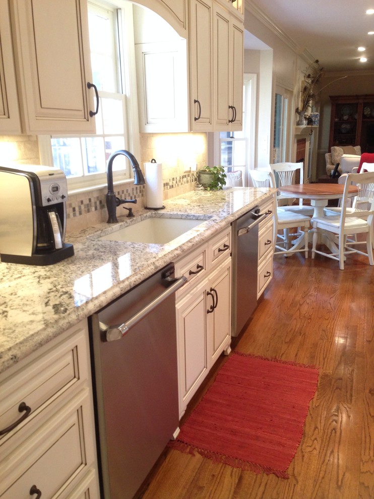 Example of a transitional medium tone wood floor kitchen design in Raleigh with granite countertops, beige backsplash, stone tile backsplash and stainless steel appliances