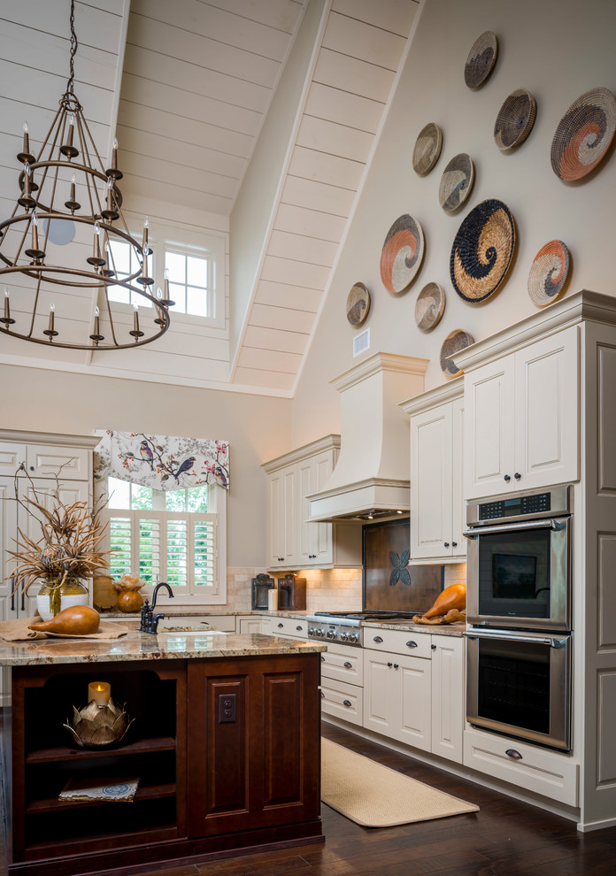 Open concept kitchen - mid-sized craftsman l-shaped dark wood floor open concept kitchen idea in Other with a farmhouse sink, recessed-panel cabinets, distressed cabinets, granite countertops, beige backsplash, stone tile backsplash, paneled appliances and an island