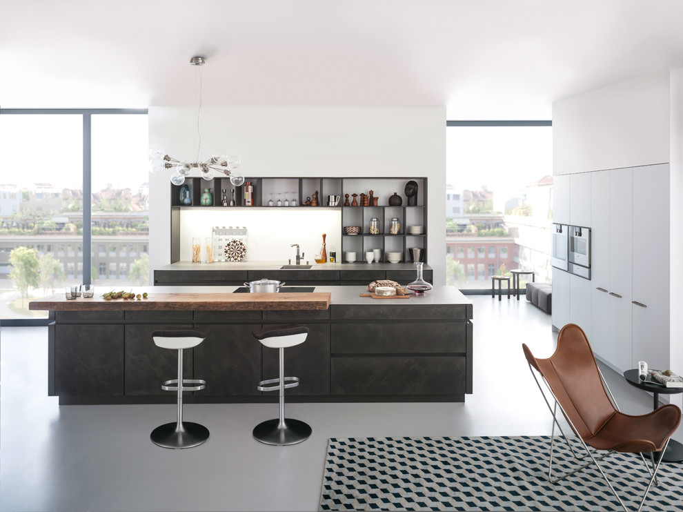 Идея дизайна: параллельная кухня-гостиная среднего размера в стиле модернизм с плоскими фасадами, врезной мойкой, серыми фасадами, столешницей из бетона, белым фартуком, техникой из нержавеющей стали, бетонным полом и островом