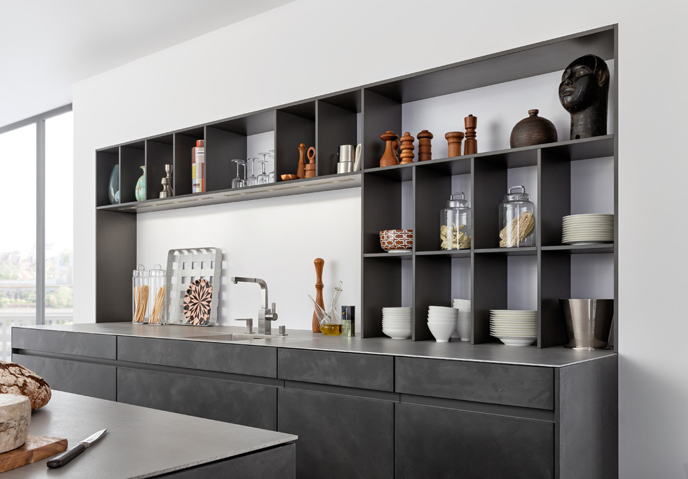 Example of a mid-sized minimalist galley concrete floor open concept kitchen design in New York with an undermount sink, flat-panel cabinets, gray cabinets, concrete countertops, white backsplash, stainless steel appliances and an island