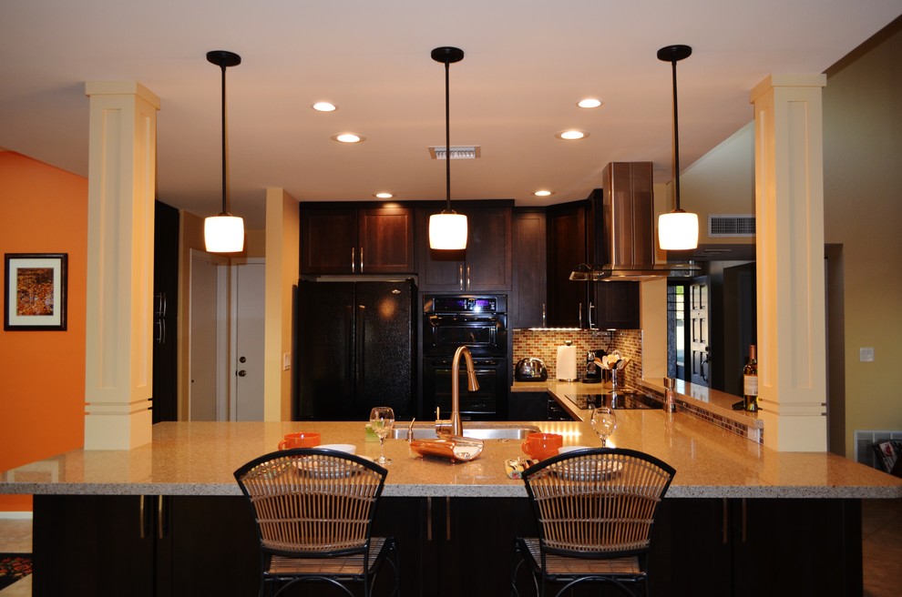 Foto på ett mellanstort funkis kök, med en undermonterad diskho, luckor med infälld panel, skåp i mörkt trä, bänkskiva i kvarts, flerfärgad stänkskydd, stänkskydd i glaskakel, svarta vitvaror, travertin golv och en halv köksö