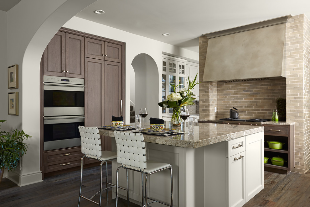 Photo of a traditional kitchen in Minneapolis with recessed-panel cabinets, dark wood cabinets, beige splashback, stainless steel appliances, dark hardwood flooring and an island.