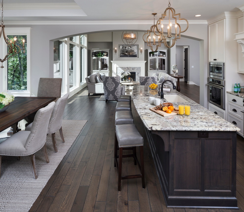 Inspiration for a large timeless u-shaped dark wood floor and brown floor open concept kitchen remodel in Minneapolis with an island, an undermount sink, recessed-panel cabinets, white cabinets, granite countertops, brown backsplash and stainless steel appliances