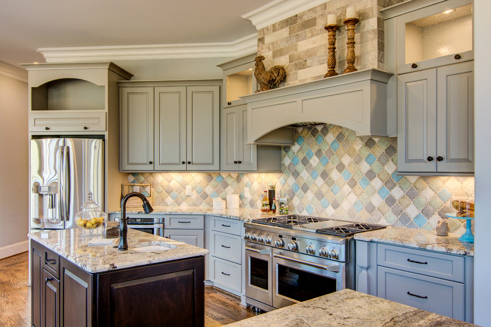 Klassische Küche mit Unterbauwaschbecken, profilierten Schrankfronten, blauen Schränken, bunter Rückwand, Küchengeräten aus Edelstahl und braunem Holzboden in Sonstige