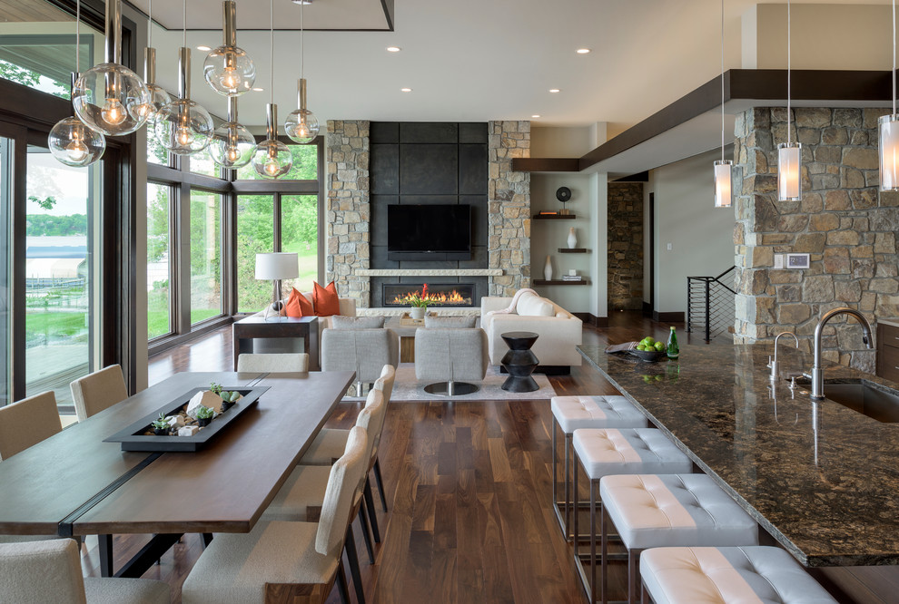 This is an example of an expansive contemporary l-shaped open plan kitchen in Minneapolis with a submerged sink, flat-panel cabinets, dark wood cabinets, granite worktops, beige splashback, stone tiled splashback, stainless steel appliances, medium hardwood flooring and an island.
